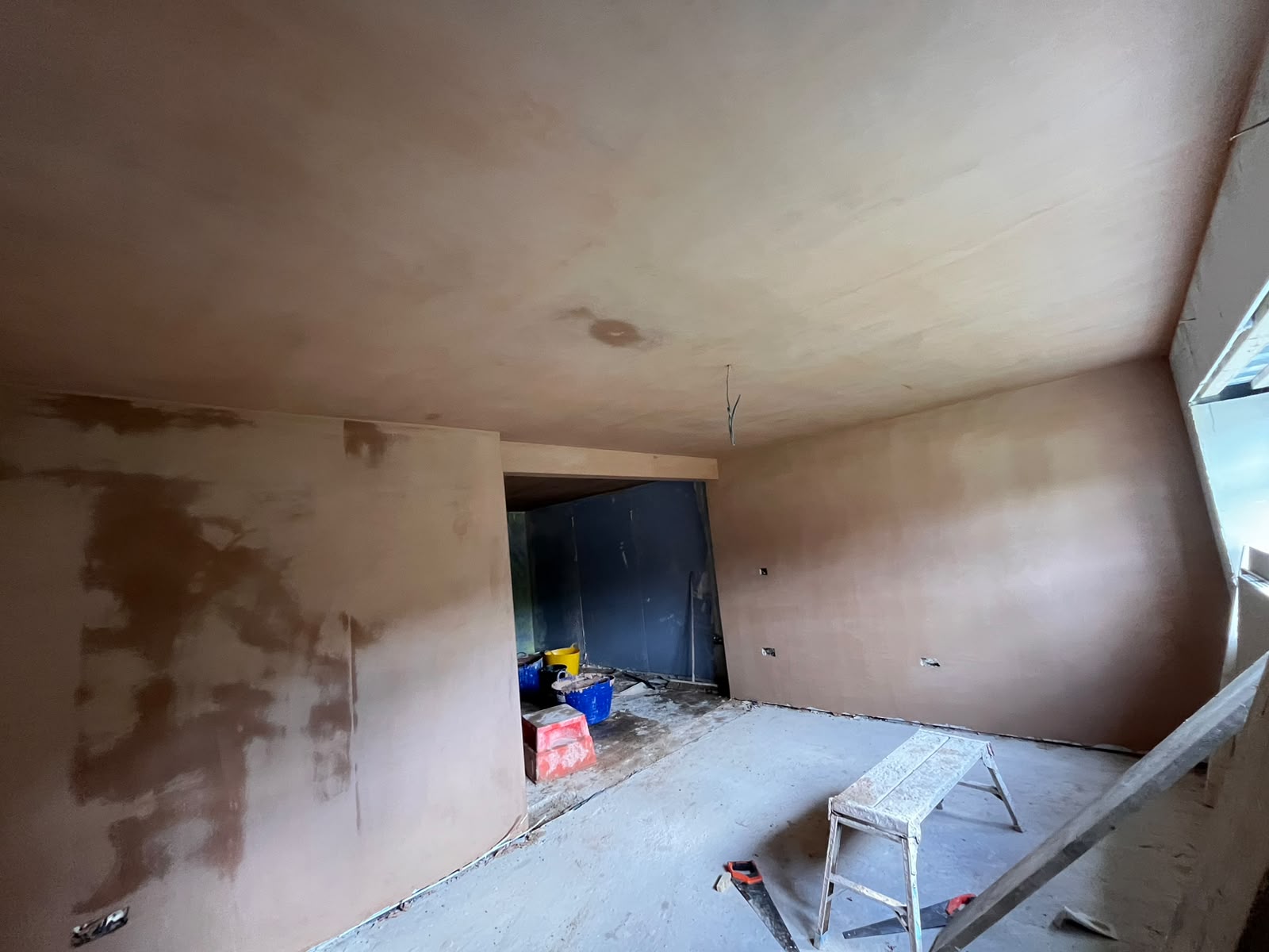 New-build interior during plastering, boarded walls, workbench and buckets