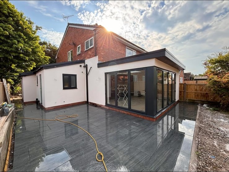 White rendered rear extension with grey patio and black-framed corner glazing