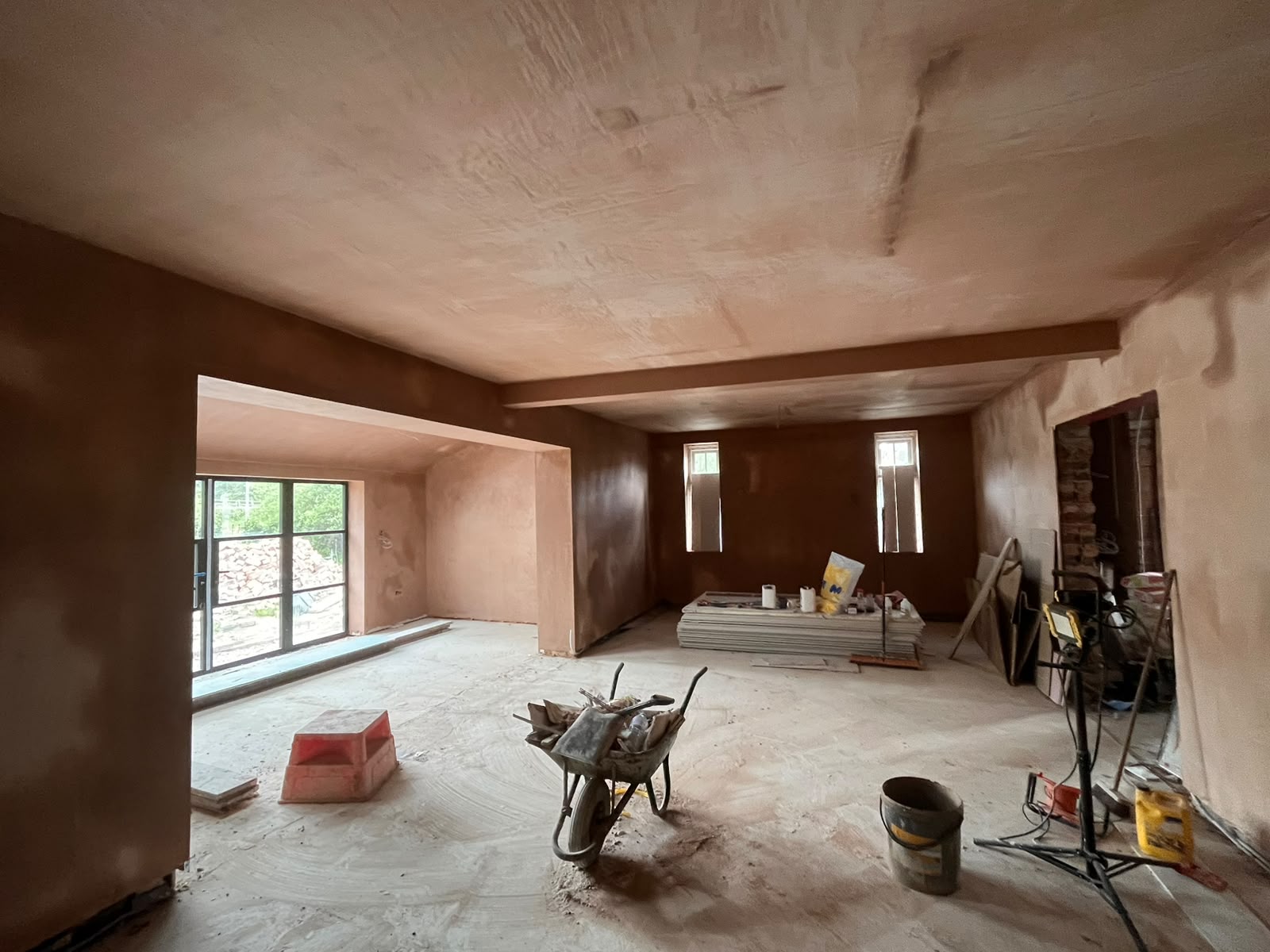 Open-plan lounge with skimmed plaster walls and ceiling, tools on the floor